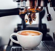 extraction de café de la machine à café avec un porte-filtre versant du café dans une tasse, expresso poruing de la machine à café au café photo
