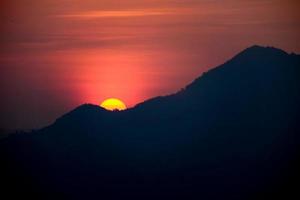 le soleil se lève derrière la montagne photo