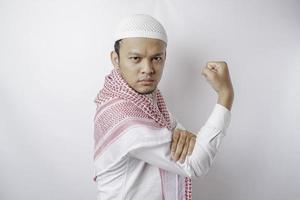 homme musulman asiatique excité montrant un geste fort en levant les bras et les muscles en souriant fièrement photo