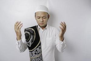 heureux bel homme musulman asiatique avec un tapis de prière sur son épaule prie Dieu. photo