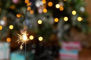 la bougie de cierges scintillants de noël brûle dans le fond de l'arbre de noël. décoration d'éclairage de noël à la maison à l'intérieur. la magie festive étincelle des lumières pour la fête de vacances. réveillon de noël avec feu d'artifice. photo