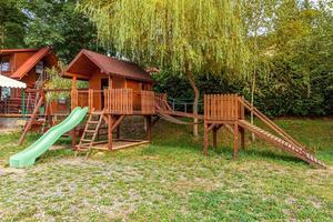 aire de jeux pour enfants en bois moderne vide située sur une cour verte dans un parc public en été. terrain de jouets amusant pour les enfants. activités d'exercice urbain pour enfant à l'extérieur. concept d'enfance de quartier. photo