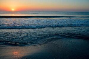 beau coucher de soleil d'été sur la plage, les vagues et le sable photo