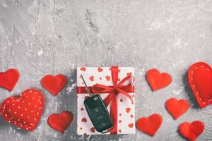 saint valentin ou autre cadeau de vacances fait à la main en papier avec des coeurs rouges, des clés de voiture et une boîte de cadeaux dans un emballage de vacances. boîte-cadeau sur la vue de dessus de table en ciment gris avec espace de copie, espace vide pour la conception photo