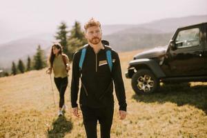 Couple souriant marchant avec des sacs à dos sur les collines verdoyantes photo