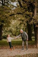 grand-père passe du temps avec sa petite-fille dans le parc le jour de l'automne photo