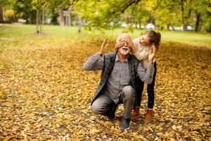 grand-père passe du temps avec sa petite-fille dans le parc le jour de l'automne photo