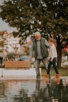 grand-père passe du temps avec sa petite-fille au bord d'une petite piscine d'eau dans le parc le jour de l'automne photo