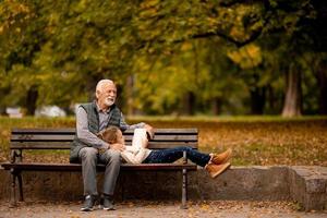 grand-père passe du temps avec sa petite-fille sur un banc dans le parc le jour de l'automne photo