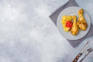 tibia de cuisse de poulet cuit au four avec légumes courgettes tomates sur une assiette. copie espace photo