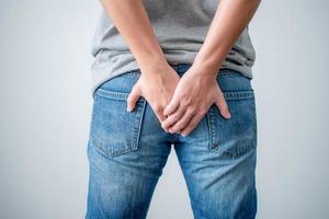 jeune homme a utilisé ses deux mains pour tenir ses fesses à cause de maux d'estomac. concept de soins de santé. photo