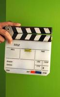 panneau d'ardoise de film ou panneau de clapet et main d'homme et couleur blanche et fond d'écran vert en studio. photo