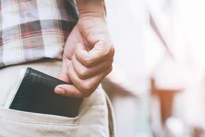 homme d'affaires confiant posant en toute sécurité en gardant votre portefeuille dans la poche arrière de son pantalon de poche arrière. économiser de l'argent. photo