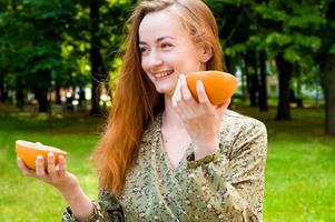 portrait d'été d'une fille souriante heureuse tenant un pamplemousse dans le parc. concept de vacances. vitamines photo