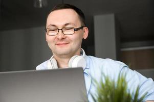 gros plan d'un homme asiatique souriant et heureux utilisant un ordinateur portable pour l'éducation en ligne ou le travail à domicile. photo