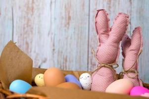 gros plan de lapins jouets roses dans le panier rempli d'œufs colorés. bannière de joyeuses pâques avec place pour le texte photo