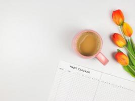 mise en page à plat du livre de suivi des habitudes, tasse de café et tulipes sur fond blanc. photo