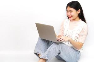 jeune femme gaie asiatique assise et utilisant un ordinateur portable. technologie et concept d'apprentissage. photo