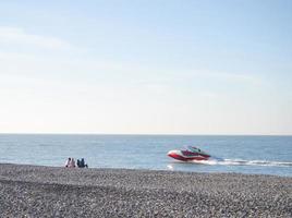 les gens sur la plage de galets de printemps. vacances à la plage. détente en mer. bord de mer rocheux. plage de galets. bateaux sur l'eau. photo