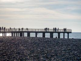 silhouettes de personnes sur le pont au bord de la mer. les gens voient le coucher du soleil. côte. jetée sur la mer. photo