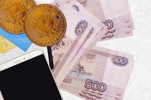 Billets de 500 roubles russes et bitcoins dorés avec smartphone et cartes de crédit. concept d'investissement en crypto-monnaie. minage ou commerce de crypto photo