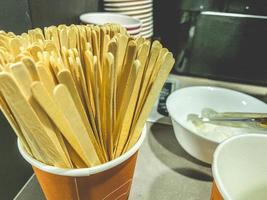 bâtons en bois pour remuer la boisson. de nombreux bâtons dans un verre en plastique. machine à café dans une station-service. préparation de boissons chaudes photo