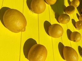 lumineux beau motif jaune d'été juteux de délicieux citrons d'agrumes vitaminés vivifiants aigres sur un fond de planches jaunes en bois. l'arrière-plan. texture photo