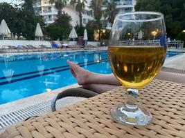 Gobelet en verre de délicieuse bière glacée fraîche fraîche devant la piscine en vacances dans un complexe tropical photo