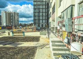 construction d'un nouveau microquartier en centre-ville. maison en blocs de béton. de la peinture blanche est appliquée sur la façade d'un immeuble de grande hauteur. peintre sur une grue peint une maison photo