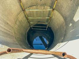 bien fait maison dans le pays. anneaux de béton descendus dans la fosse. l'eau est tirée d'un puits à l'aide d'un seau. puits profond, eau de terre. utilisation des ressources naturelles photo