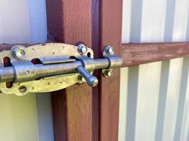 boulon de fer pour fermer la porte sur une clôture ou un garage. un loquet pour fermer les portes en carton ondulé métallique. l'arrière-plan photo