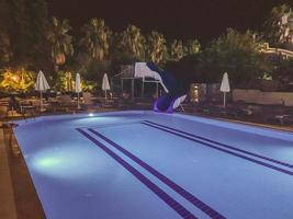 piscine à l'hôtel le soir, eau bleue dans la piscine. reste de touristes près de l'eau le soir. repos au bord de l'eau, toboggans aquatiques, balade au bord de l'eau photo