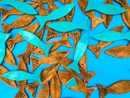 poisson de mer en bois. application, poisson blanc et brun en matériaux naturels. appât pour la pêche, poisson sur fond bleu mat photo