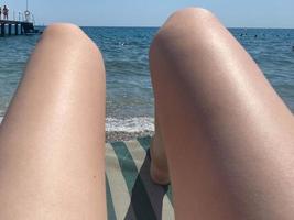 partie basse de la jeune femme profitant du soleil sur une chaise longue au bord de la piscine pendant les vacances d'été photo