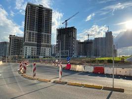 réparation et construction d'une route avec des panneaux de signalisation temporaires et des cônes sur fond de beaux grands bâtiments neufs sur fond de ciel bleu et d'arc-en-ciel dans une grande ville photo