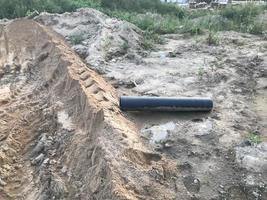 saleté sur un chantier de construction. sillons de sable des tracteurs et des finisseurs. sillons de sable, traces de véhicules lourds. il y a un tuyau en plastique à proximité, établissant des communications pour les maisons photo