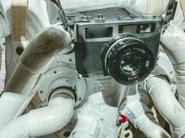 costume blanc avec astronaute de combinaison spatiale dans l'espace. il a un petit appareil photo vintage accroché autour du cou. filmer dans l'ambiance