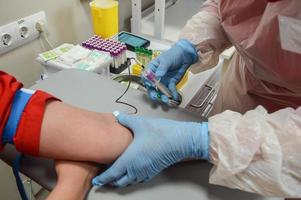 une infirmière insère une aiguille dans une veine sur un bras patient. procédure de prélèvement sanguin photo