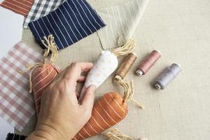 la main d'une femme âgée tenant une carotte en tissu. couture et travaux d'aiguille de pâques, artisanat facile et créatif pour la famille, décoration de pâques photo