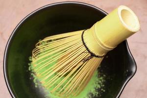 processus de cuisson du thé vert matcha dans un bol noir avec un fouet en bambou. poudre de matcha de thé vert biologique. mise au point sélective. photo