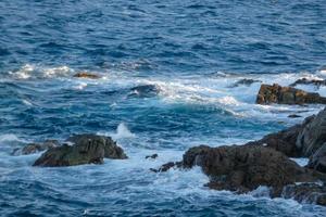 mer atteignant les rochers créant des éclaboussures d'écume photo