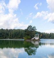 une petite île magnifique sur le lac aya dans le territoire de l'altaï ou la république de l'altaï. il y a un petit belvédère sur l'île et une forêt autour du lac. photo