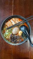 vue de dessus. ramen miso épicé. nouilles japonaises aux légumes, poulet rôti haché, algues et œuf à la coque photo