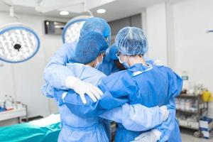 vue partielle de l'équipe hospitalière masculine et féminine qui travaille dur, en tenue de protection complète, debout ensemble dans une étreinte de groupe. photo