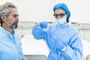 homme mûr recevant un test pcr pour le coronavirus lors d'un rendez-vous au cabinet du médecin. le médecin effectue un test pcr sur écouvillon de coronavirus tout en portant un masque de protection du visage pendant la pandémie de covid-19. photo