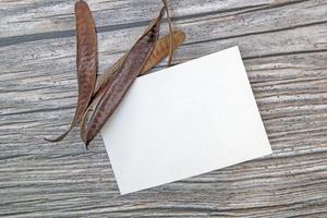 maquette de carte de voeux en papier a5 avec des feuilles sèches sur fond de bois photo