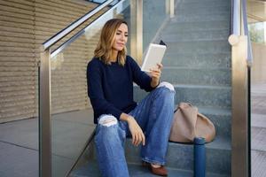 femme lisant un livre électronique sur les marches photo