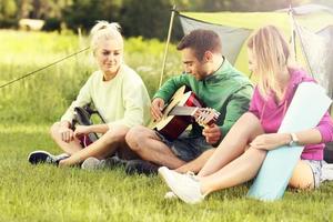 groupe d'amis campant dans la forêt et jouant de la guitare photo