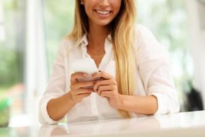 Portrait de jeune femme avec café et smartphone dans la cuisine photo