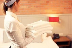 femme de ménage avec des serviettes propres dans la chambre d'hôtel photo